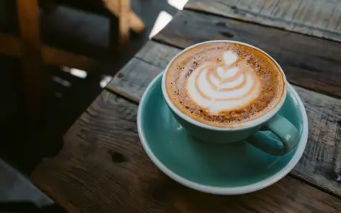 Aromaticzna kawa ristretto z pianką latte art na drewnianym blacie. Idealny poranek.