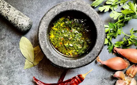 Frische Kräuter, Knoblauch, Schalotten und Chili – die chimichurri hauptzutaten werden im Mörser zubereitet.