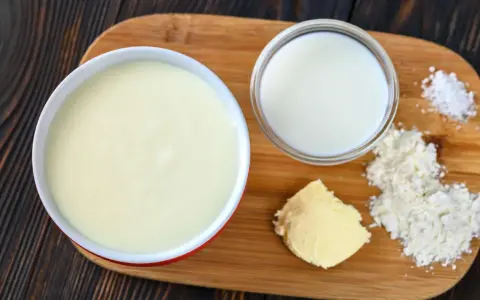 Zutaten für eine Mehlschwitze: Butter, Mehl, Milch und Salz auf einem Holzbrett.