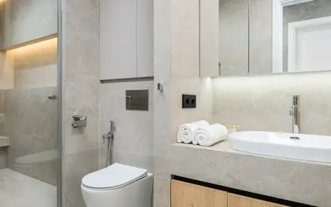 Modernt kaklat badrum med dusch, toalett och handfat. Ljus och stilren design.