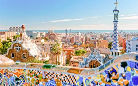 Kolorowe mozaiki i bajkowe budowle w Parku Güell z widokiem na Barcelonę.