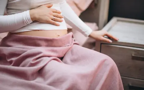 Ciąża i zgaga? Delikatny dotyk brzucha, różowy koc i myśl o tym, co na zgagę w ciąży.