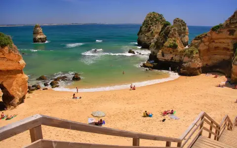 Sonnige Bucht mit goldenem Sand und Felsformationen. Ein perfekter Ort für einen entspannten Tag am Meer, nur eine kurze Fahrt vom Flughafen Portugal Algarve entfernt.