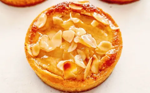Un délicieux gâteau poire amandine, doré et garni d'amandes effilées, prêt à être dégusté.