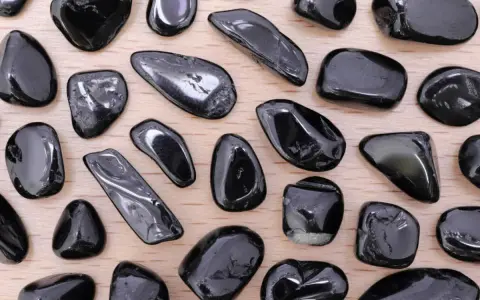 Tormalina nera, nota per le sue proprietà protettive e di radicamento, in una collezione di pietre levigate su fondo di legno.