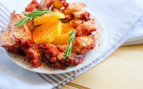 Un invitante polpo alla gallega, cosparso di paprika e guarnito con rosmarino e patate, pronto per essere gustato.