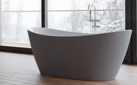Une baignoire moderne dans une chambre, avec une grande fenêtre offrant une vue sur un paysage enneigé. Parfait pour un moment de détente.