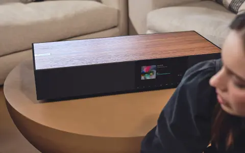 Elegancki Cambridge Audio One z drewnianym blatem i ekranem odtwarza muzykę.