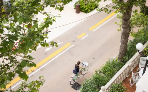 Una donna in bicicletta percorre il lungomare di San Mauro Mare, su una pista ciclabile ben segnalata.