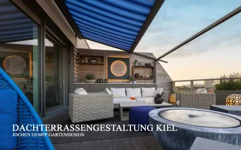 Gemütliche Dachterrasse mit Lounge-Möbeln, blauem Sonnensegel und Blick auf die Stadt.