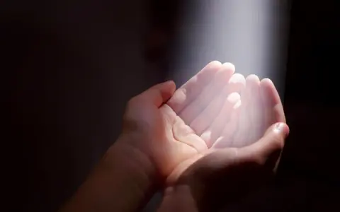Hände im Licht, die Hoffnung suchen. Ein Symbol für gott und das Leid, das durch Glauben überwunden werden kann.