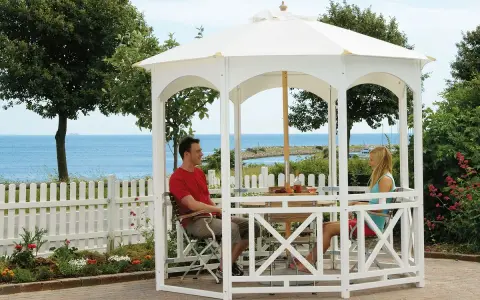 Ett par njuter av utsikten vid havet under en vit paviljong. Perfekt för att bygga paviljong och skapa en avkopplande oas.
