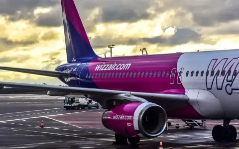Samolot Wizz Air na płycie lotniska pod pochmurnym niebem.