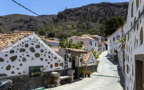 Urokliwa uliczka z białymi domami i kamiennymi zdobieniami na Gran Canarii. Odkryj te i inne **Gran Canaria atrakcje**!