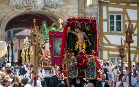 Prozession mit Jesus-Figur und Blumen. Fronleichnam ist ein gesetzlicher Feiertag, an dem solche Umzüge stattfinden.