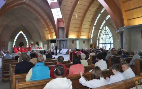 Nabożeństwo w kościele św. Jakuba w Łebie. Wierni siedzą w ławkach, a przy ołtarzu odprawiana jest msza.