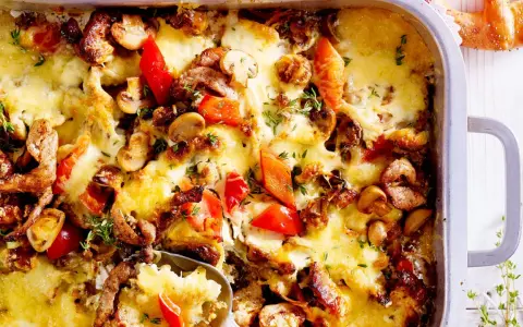 Herzhafter Gyros Auflauf mit geschmolzenem Käse, Pilzen und Paprika, garniert mit frischen Kräutern.