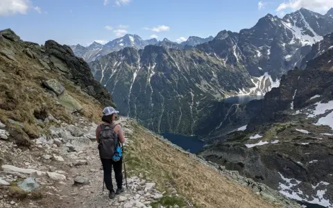 Trasa na Szpiglasowy Wierch. Turystka z plecakiem idzie kamienistym szlakiem, podziwiając widok na Tatry i Morskie Oko.