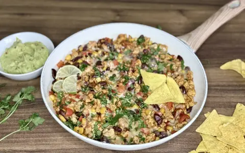 Pyszny kurczak po meksykańsku z fasolą, kukurydzą i serem, podany z guacamole i nachos.
