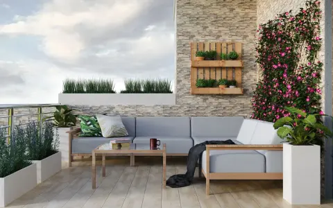 Przytulny balkon w bloku z szarą sofą, drewnianym stolikiem i kwitnącym bluszczem. Idealne miejsce na relaks po myciu balkonu w bloku.