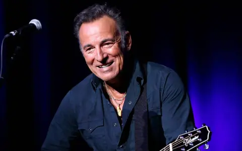 Bruce Springsteen ler glatt på scenen i Sverige, med gitarr och mikrofon redo för en oförglömlig kväll.