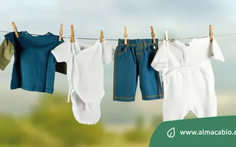 Baby clothes hanging on a clothesline: a blue long-sleeve shirt, a white onesie, blue shorts, and a white romper.