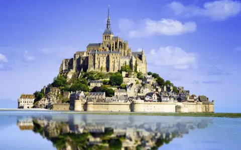 Opactwo Mont Saint-Michel, jeden z najpiękniejszych miejsc we Francji, odbija się w spokojnej wodzie.