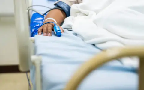 Paciente en cama de hospital con oxímetro en el dedo, indicando la necesidad de permiso por enfermedad.