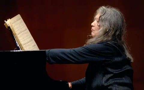 Martha Argerich, pianistka o argentyńskim pochodzeniu, gra na fortepianie, wpatrzona w nuty.