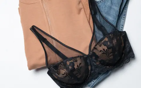 Un reggiseno di pizzo nero adagiato su jeans e felpa color cammello. Pensando a ogni quanto si cambia il reggiseno, questo è un capo che merita cura.