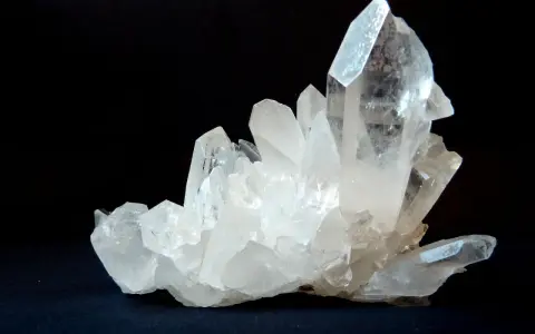 Un grappolo di cristalli di quarzo trasparenti e luminosi su sfondo scuro. Questo è un esempio di che cos'è il quarzo, un minerale comune e versatile.