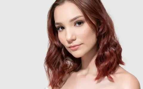 Mahoń kolor włosów komu pasuje? Modelka z rudymi, falowanymi włosami prezentuje ten odcień.