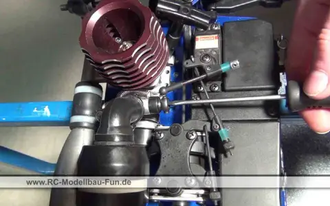Nahaufnahme eines Nitromethan-Autos, bei dem eine Hand mit einem Schraubendreher an der Mechanik arbeitet.