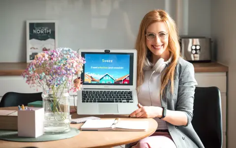 Uśmiechnięta kobieta prezentuje laptop z napisem "Z nami pokochasz język szwedzki!". Idealna dla studentów filologii szwedzkiej w Warszawie.