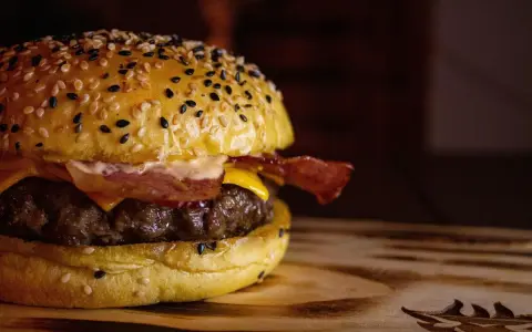Soczysty burger z bekonem i serem na bułce z sezamem.