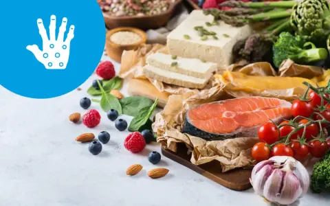 Zdrowa dieta przy łuszczycy: łosoś, warzywa, owoce, orzechy i tofu. Ikona dłoni symbolizuje ulgę.