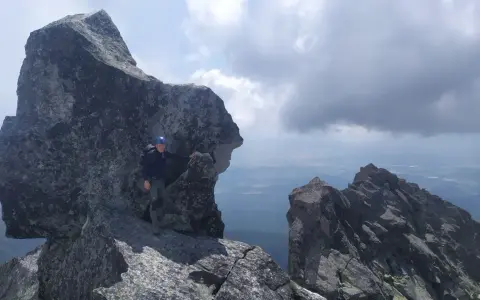 Wspinacz w kasku na skalistym szczycie, podziwiający widok. Tatry poza szlakiem, gdzie każdy krok to przygoda.