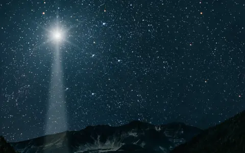 Jasna gwiazda betlejemska świeci na nocnym niebie nad górami, wskazując drogę.