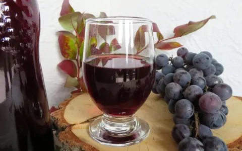 Wino z ciemnych winogron, kieliszek, kiść winogron i butelka. Idealne na przepis na wino z ciemnych winogron.