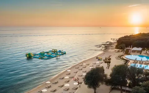 Zachód słońca nad morzem przy plaży z dmuchanym placem zabaw i basenem. Idealne miejsce na wakacje w camping Vrila.