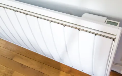 Radiateur électrique blanc installé sur un parquet. Un écran affiche la température. Guide pour comment installer un radiateur électrique.