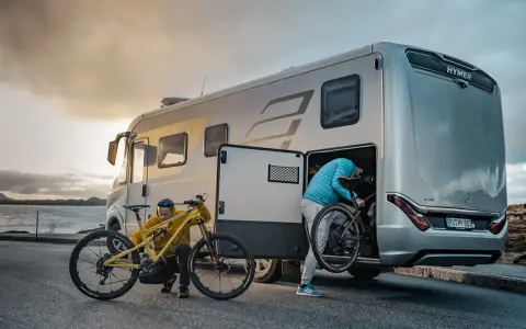 Zwei Personen laden Mountainbikes in einen Hymer Wohnwagen. Perfekt für Abenteuer mit dem e-bike wohnwagen.