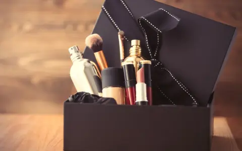 Schwarze Geschenkbox mit Kosmetikartikeln wie Parfüm, Lippenstift und Make-up-Pinseln.