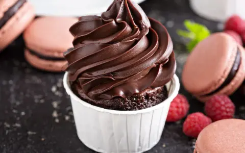 Gourmandise chocolatée : un cupcake avec ganache montée, macarons et framboises. Idéal pour la conservation ganache montée frigo.