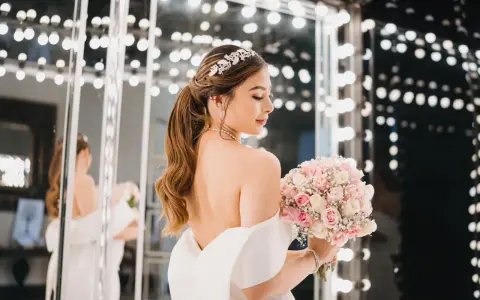 Novia con peinados de novia recogidos elegantes, tiara brillante y ramo de rosas.