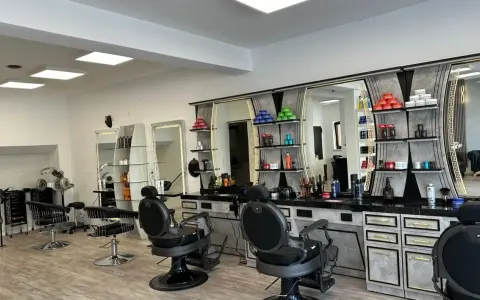 Friseurstuhl und Spiegel in einem modernen Salon mit Regalen voller Kosmetikprodukte.