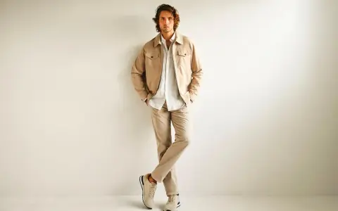 Hombre con ropa business casual en tonos beige: chaqueta, camisa y pantalones.