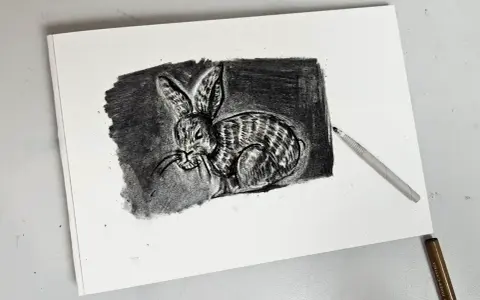 Un detallado dibujo carboncillo de un conejo con rayas, con un lápiz de carboncillo apoyado sobre el papel.