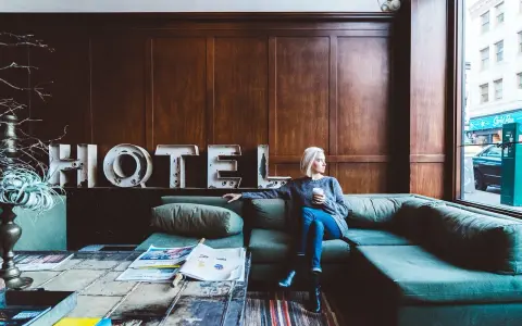 Kobieta siedzi na kanapie w hotelu, zastanawiając się, ile zarabia technik hotelarstwa.