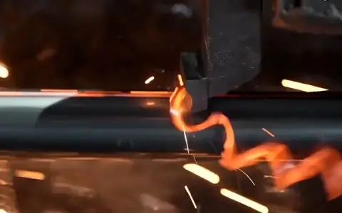Glühender Baustahl wird geformt, Funken sprühen. Die immense Festigkeit des Materials wird sichtbar, während es sich biegt.